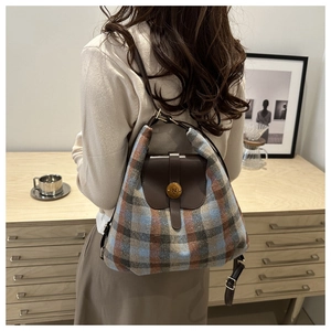 Detail of vintage gold buckle with N engraving on plaid wool backpack with leather trim