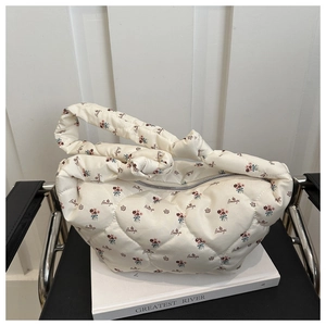 Close-up of white floral quilted nylon dumpling bag with red floral pattern and knot strap