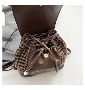 Detail view of houndstooth fabric and brown faux leather trim on a vintage backpack