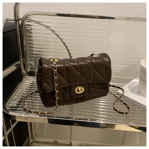 Détail d'un sac matelassé marron foncé avec cuir brillant et fermoir en métal doré