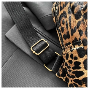Detail of leopard print backpack with black nylon strap and gold metal buckle hardware