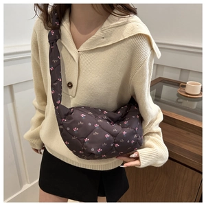 Detail view of brown quilted nylon crossbody bag with pink floral pattern and text