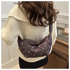 Detail of dark brown quilted floral crossbody bag with wide padded shoulder strap