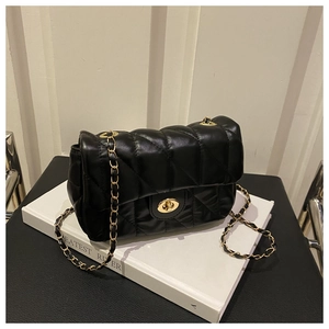 Détail d'un sac bandoulière en cuir noir matelassé avec chaîne dorée et fermoir rotatif