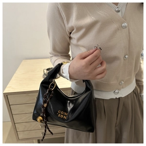 Detail of black leather hobo bag with gold logo, woven cord and metallic sphere charm