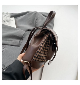 Detail of vintage houndstooth patterned mini backpack with brown leather trim and straps