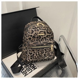 Detail of leopard print mini backpack showing gold zippers and metallic nameplate