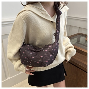 Detail of dark brown quilted nylon crescent bag with pink floral print and lettering