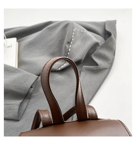 Close-up of premium dark brown leather stitching and handle on a vintage backpack