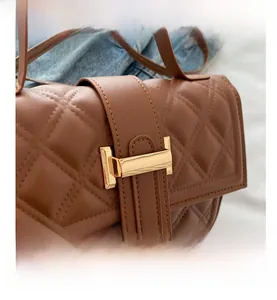 Detailansicht der braunen Stepptasche mit goldenem H-Verschluss und Lederriemen