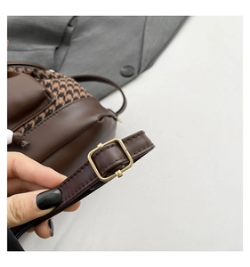 Close-up of adjustable strap with gold buckle on houndstooth pattern backpack