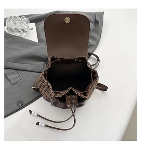 Detail view of houndstooth patchwork backpack with brown leather and drawstring closure
