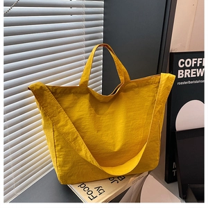 Detail of a bright yellow nylon tote bag with pleated texture and wide shoulder strap