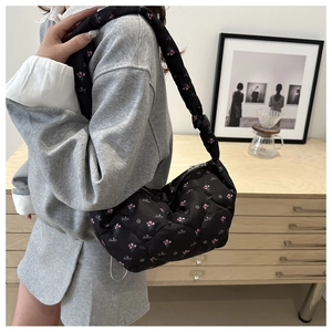 Détail du sac matelassé noir avec imprimé floral rose et texte brodé en italique