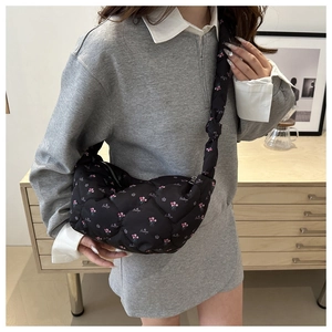 Detail of black quilted nylon moon bag with floral patterns and a decorative knot strap