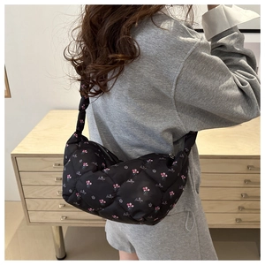 Close-up of black quilted dumpling bag featuring floral patterns and embroidered details