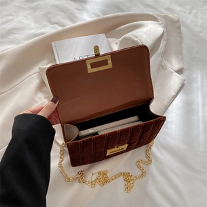 Brown velvet crossbody bag with gold chain strap and square metal lock in a top-down view