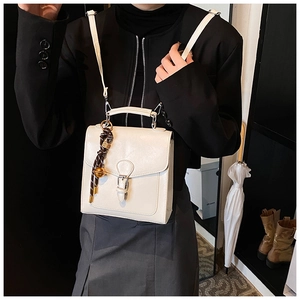 Detail of a beige leather crossbody bag with a vintage charm and metallic buckle
