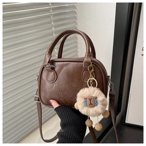 Detail of coffee brown leather bag with Lucky OHIO embossed text and soft plush charm