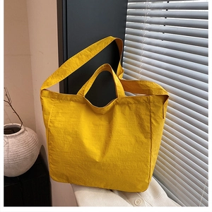 Detailed shot of yellow nylon tote bag with pleated texture and adjustable strap