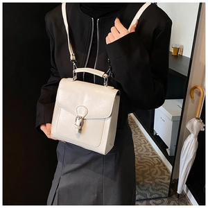 Detail of off-white faux leather mini backpack showing metallic buckle and handle texture