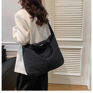 Side view of a black nylon tote bag on a model showing large capacity and soft texture