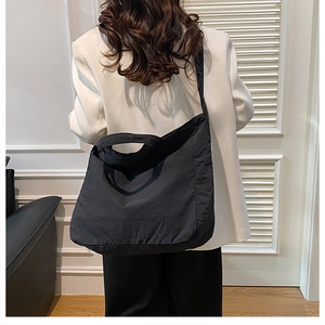 Model showing a black lightweight nylon tote bag worn over the shoulder in a bright room
