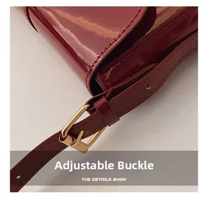 Macro detail of wine red patent leather bag showing gold pin buckle adjustment on strap