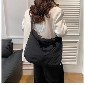 Rear view of model wearing a large black canvas tote bag with shoulder straps for commuting