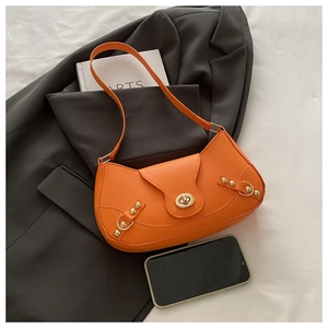 Close-up of vibrant orange patchwork underarm bag with gold twist lock and rivet details
