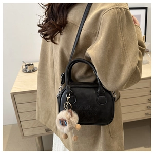 Nahaufnahme der schwarzen Retro-Schultertasche mit Prägung und süßem Schaf-Anhänger