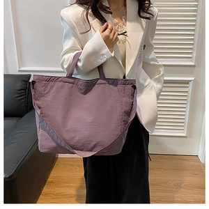 Detailed view of a purple large capacity canvas tote bag with shoulder strap worn by model