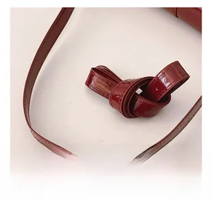Close-up of glossy burgundy patent leather shoulder straps with detailed stitching
