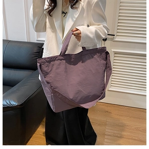 Detail of purple nylon tote bag showing soft pleated texture and handle stitching