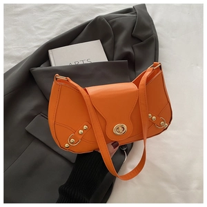 Detailed close-up of a bright orange leather underarm bag with gold turn-lock and studs