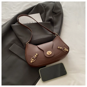 Detailed view of brown leather bag with gold buckle and rivets on grey blazer fabric