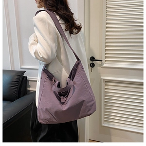 Detail of a purple minimalist tote bag showing soft nylon texture and wide shoulder strap