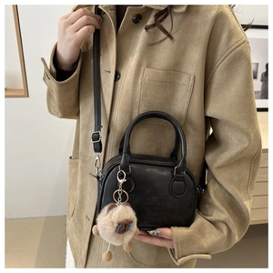 Detail of black retro handbag with lucky OHIO embossing and cute plush animal charm