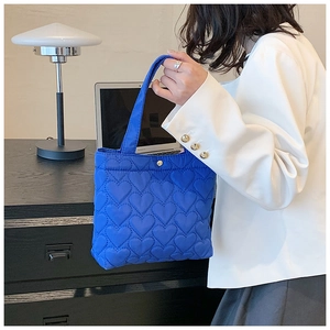 Detail of Klein blue tote bag featuring heart-shaped quilting and silver magnetic closure
