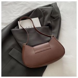 Chic dark brown faux leather hobo bag with gold hardware on a tailored grey suit jacket