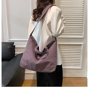 Purple nylon tote bag with adjustable strap shown in a stylish minimalist interior setting