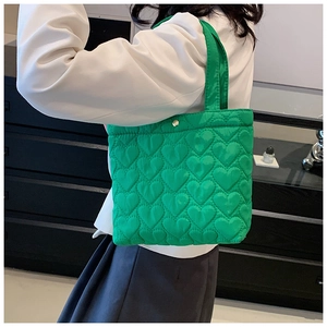 Detail of green heart-quilted tote bag featuring soft nylon fabric and gold metal clasp