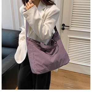Macro detail of deep purple nylon tote bag featuring reinforced straps and pleated texture