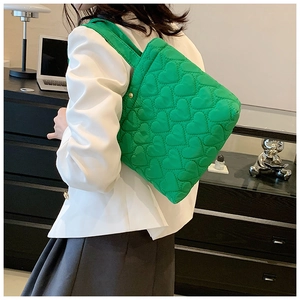 Close-up of green quilted tote bag with heart patterns shown on model shoulder
