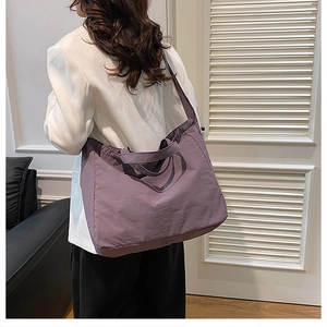 Macro shot of purple nylon tote bag with crinkled texture worn by a model in white blazer