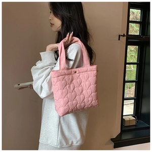 Detail of pink heart-quilted tote bag featuring lightweight fabric and snap closure