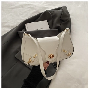 Close-up of white leather crescent shoulder bag with golden hardware and stud details