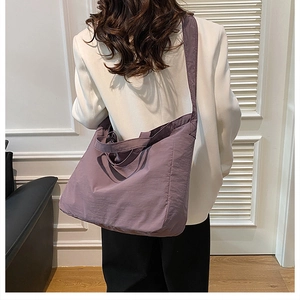 Detail view of purple nylon tote bag with wide strap and waterproof texture on shoulder