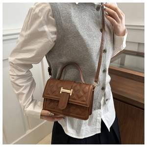 Detailansicht der braunen Stepptasche mit goldenem H-Verschluss und Leder-Schultergurt
