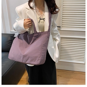 Close-up of a purple nylon tote bag on a model in a minimalist bright indoor setting